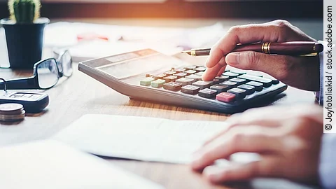 Rechnung Ein Mann tippt etwas in einen Taschenrechner. Vor ihm liegt ein Blatt Papier.
