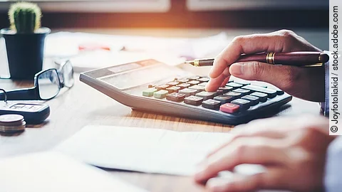 Rechnung Ein Mann tippt etwas in einen Taschenrechner. Vor ihm liegt ein Blatt Papier.