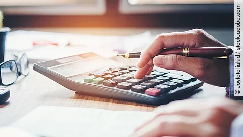 Ein Mann tippt etwas in einen Taschenrechner. Vor ihm liegt ein Blatt Papier.