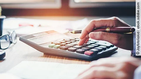 Rechnung Ein Mann tippt etwas in einen Taschenrechner. Vor ihm liegt ein Blatt Papier.