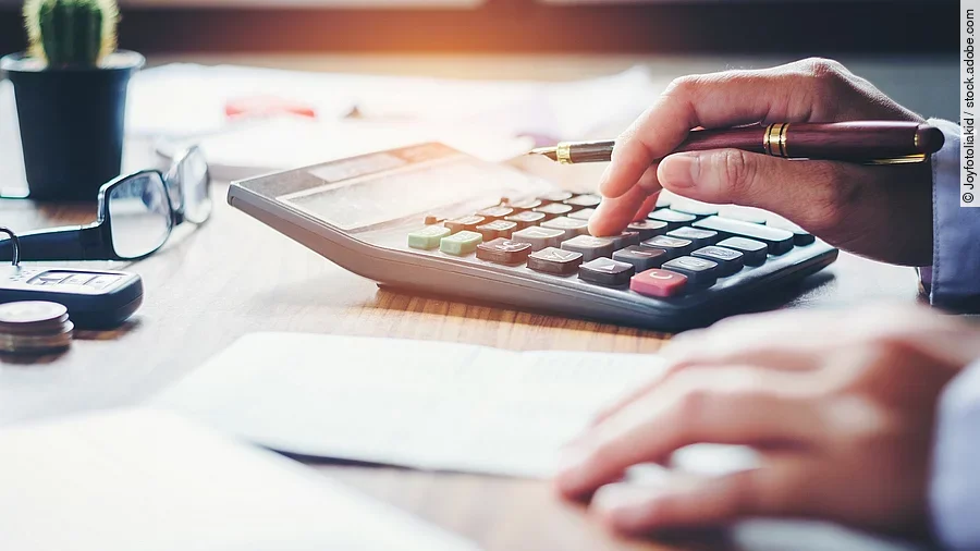 Rechnung Ein Mann tippt etwas in einen Taschenrechner. Vor ihm liegt ein Blatt Papier.