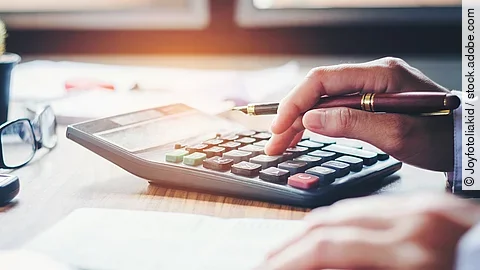 Rechnung Ein Mann tippt etwas in einen Taschenrechner. Vor ihm liegt ein Blatt Papier.