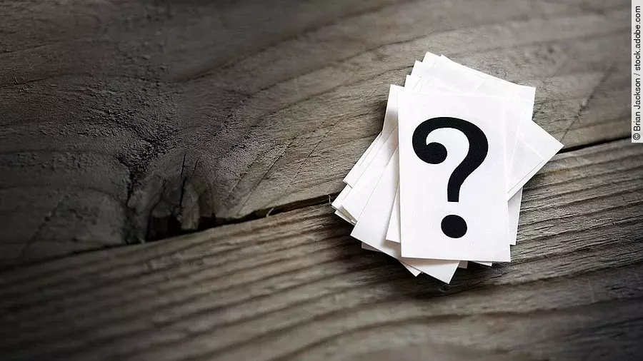 Fragezeichen Weiße Karten mit Fragezeichen liegen auf einem Holztisch