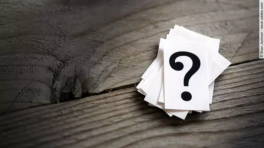 Fragezeichen Weiße Karten mit Fragezeichen liegen auf einem Holztisch