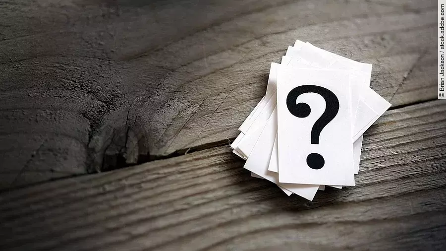 Fragezeichen Weiße Karten mit Fragezeichen liegen auf einem Holztisch