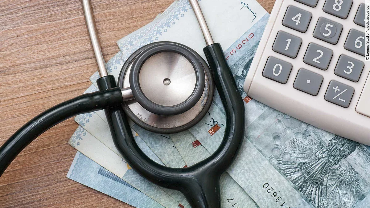 Taschenrechner und Stethoskop liegen auf Geldscheinen