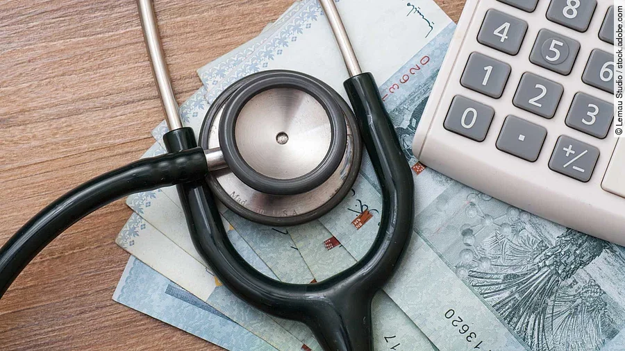 Taschenrechner und Stethoskop liegen auf Geldscheinen