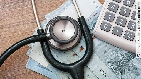 Taschenrechner und Stethoskop liegen auf Geldscheinen