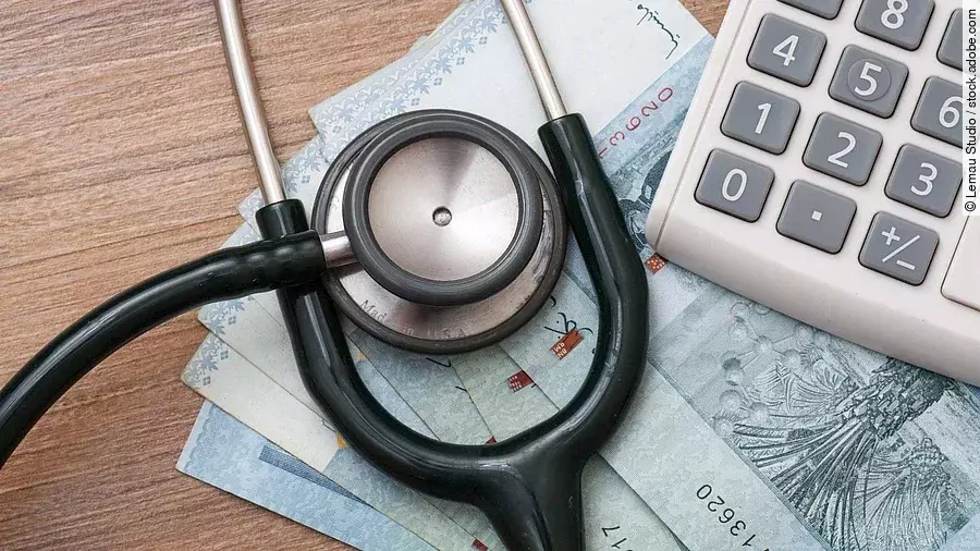 Taschenrechner und Stethoskop liegen auf Geldscheinen