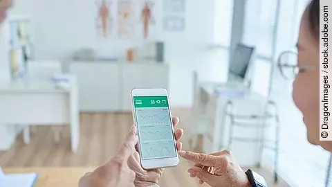 Gesundheitsapp Zwei Personen begutachten die Auswertung einer Gesundheitsapp auf dem Smartphone.