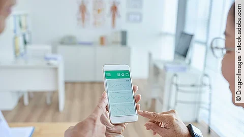 Zwei Personen begutachten die Auswertung einer Gesundheitsapp auf dem Smartphone. 