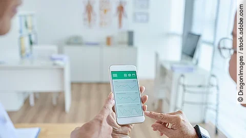 Zwei Personen begutachten die Auswertung einer Gesundheitsapp auf dem Smartphone. 