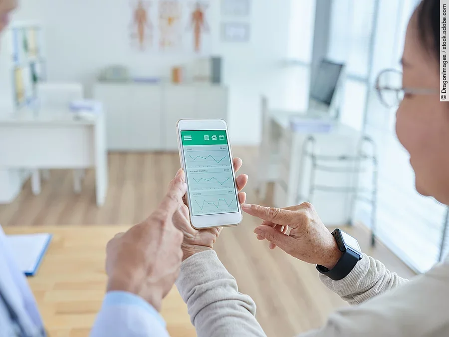 Gesundheitsapp Zwei Personen begutachten die Auswertung einer Gesundheitsapp auf dem Smartphone.