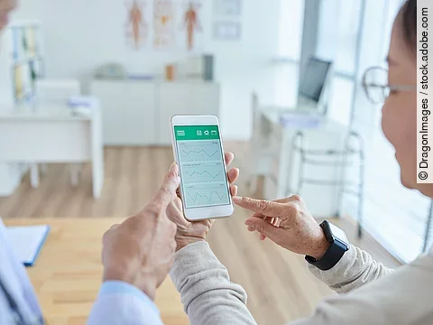 Zwei Personen begutachten die Auswertung einer Gesundheitsapp auf dem Smartphone. 