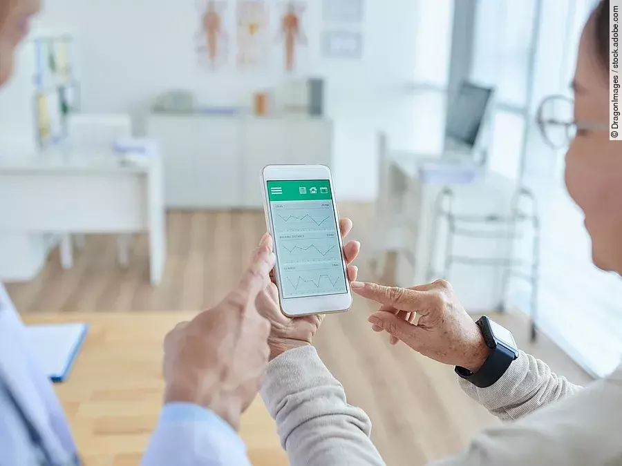 Zwei Personen begutachten die Auswertung einer Gesundheitsapp auf dem Smartphone. 