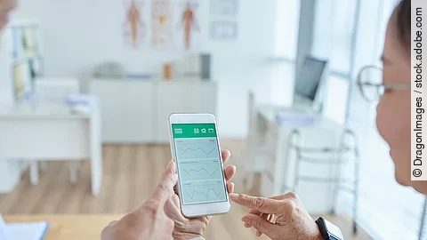 Zwei Personen begutachten die Auswertung einer Gesundheitsapp auf dem Smartphone. 