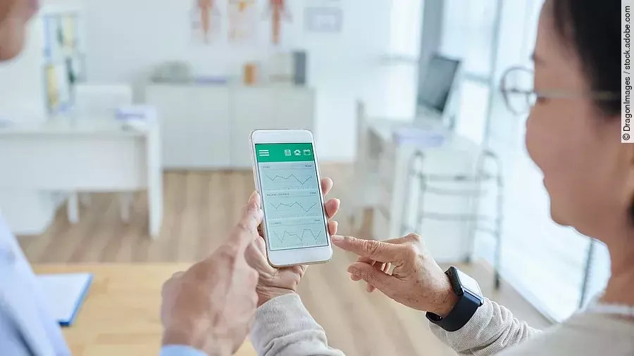 Gesundheitsapp Zwei Personen begutachten die Auswertung einer Gesundheitsapp auf dem Smartphone.