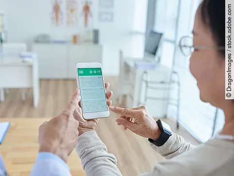Zwei Personen begutachten die Auswertung einer Gesundheitsapp auf dem Smartphone. 