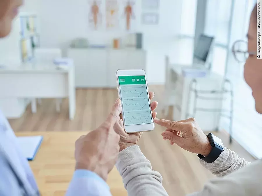 Zwei Personen begutachten die Auswertung einer Gesundheitsapp auf dem Smartphone. 