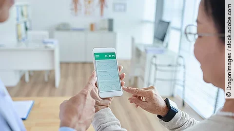 Zwei Personen begutachten die Auswertung einer Gesundheitsapp auf dem Smartphone. 