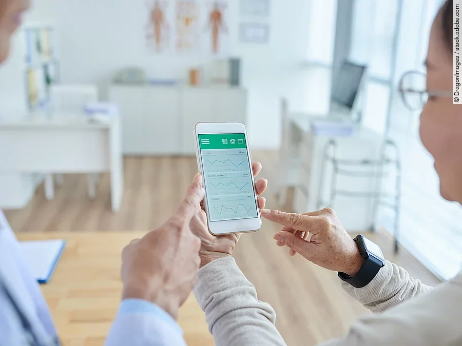 Zwei Personen begutachten die Auswertung einer Gesundheitsapp auf dem Smartphone. 