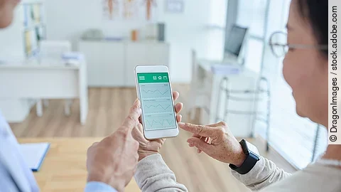 Zwei Personen begutachten die Auswertung einer Gesundheitsapp auf dem Smartphone. 