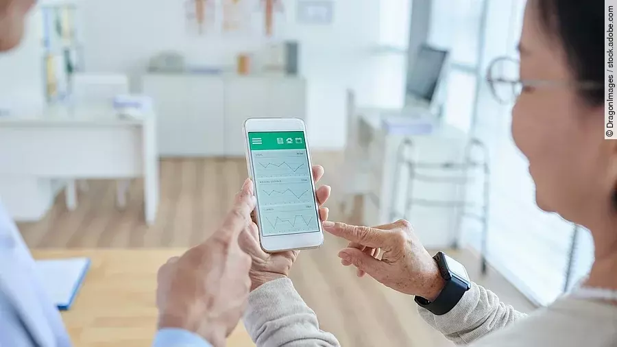 Zwei Personen begutachten die Auswertung einer Gesundheitsapp auf dem Smartphone. 