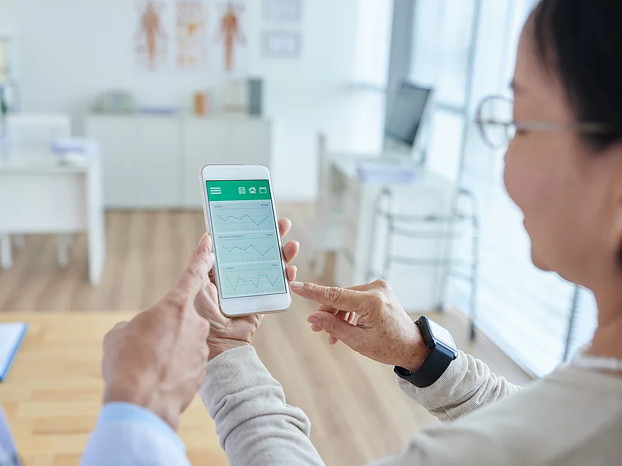 Gesundheitsapp Zwei Personen begutachten die Auswertung einer Gesundheitsapp auf dem Smartphone.