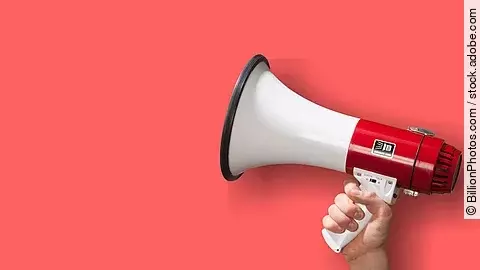 Megaphon wird vor roten Hintergrund gehalten.