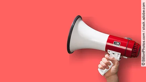 Megaphon wird vor roten Hintergrund gehalten.