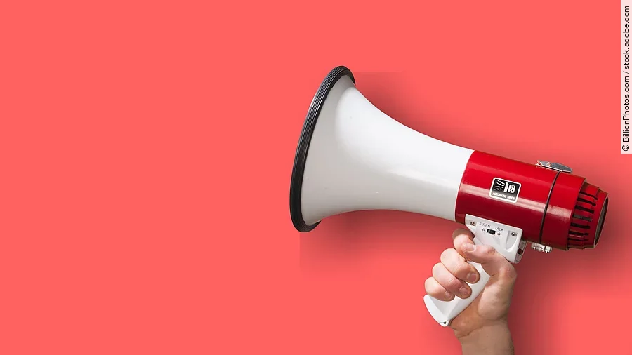 Megaphon wird vor roten Hintergrund gehalten.