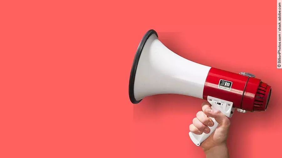 Megaphon wird vor roten Hintergrund gehalten.