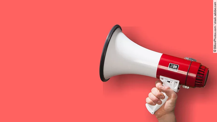 Megaphon wird vor roten Hintergrund gehalten.