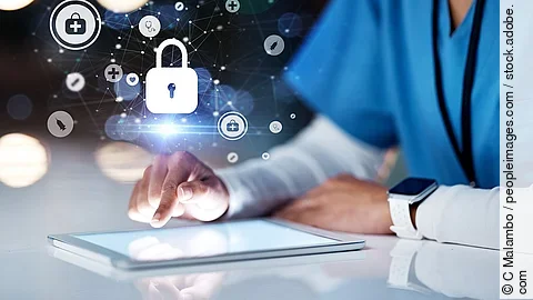 Eine Person in Kasack sitzt vor einen Tablet. Über dem Gerät erscheinen Symbole, wie ein Schloss und andere Icons, die ein  Daten veranschaulichen.