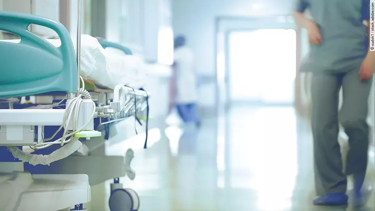 Krankenhausflur mit einem leeren Bett und einer Pflegefachkraft