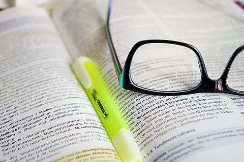Buch mit Textmarker und Brille