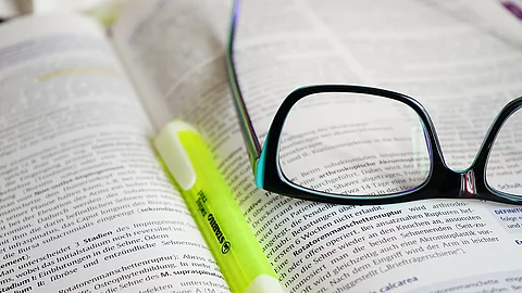 Buch mit Textmarker und Brille