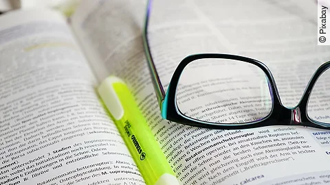 Buch mit Textmarker und Brille