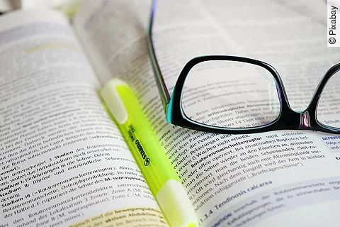 Buch mit Textmarker und Brille