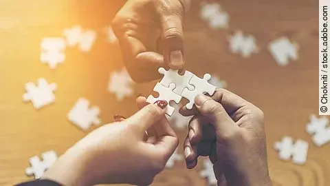Drei Hände setzen drei Puzzlestücke zusammen