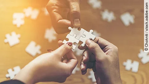 Zusammenschluss Drei Hände setzen drei Puzzlestücke zusammen