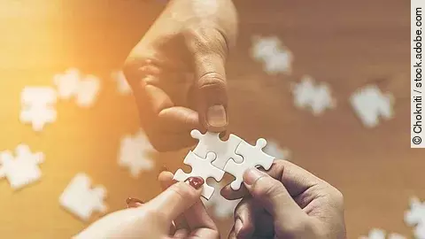 Drei Hände setzen drei Puzzlestücke zusammen