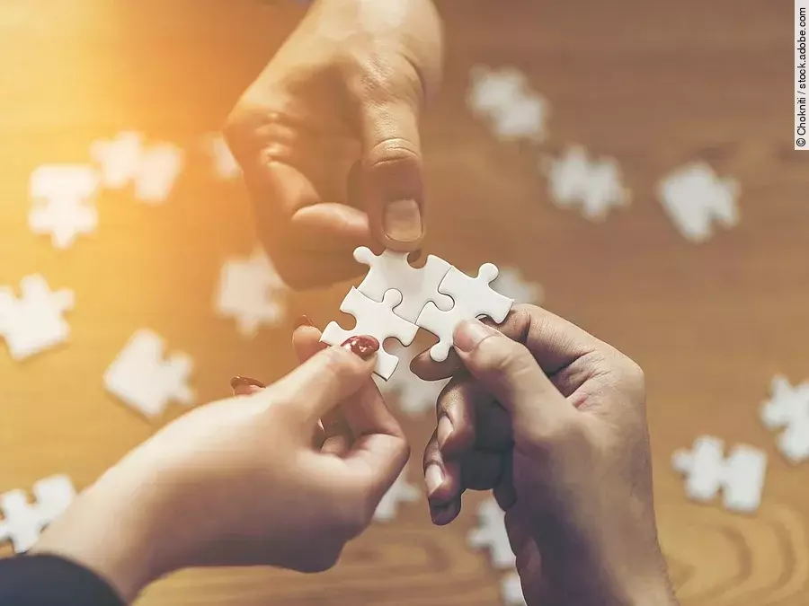 Drei Hände setzen drei Puzzlestücke zusammen