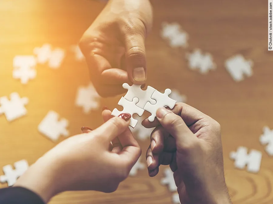 Drei Hände setzen drei Puzzlestücke zusammen