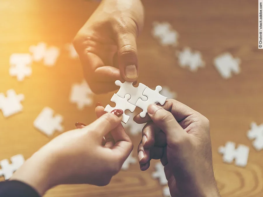 Zusammenschluss Drei Hände setzen drei Puzzlestücke zusammen