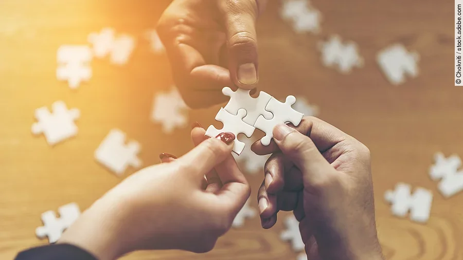 Zusammenschluss Drei Hände setzen drei Puzzlestücke zusammen
