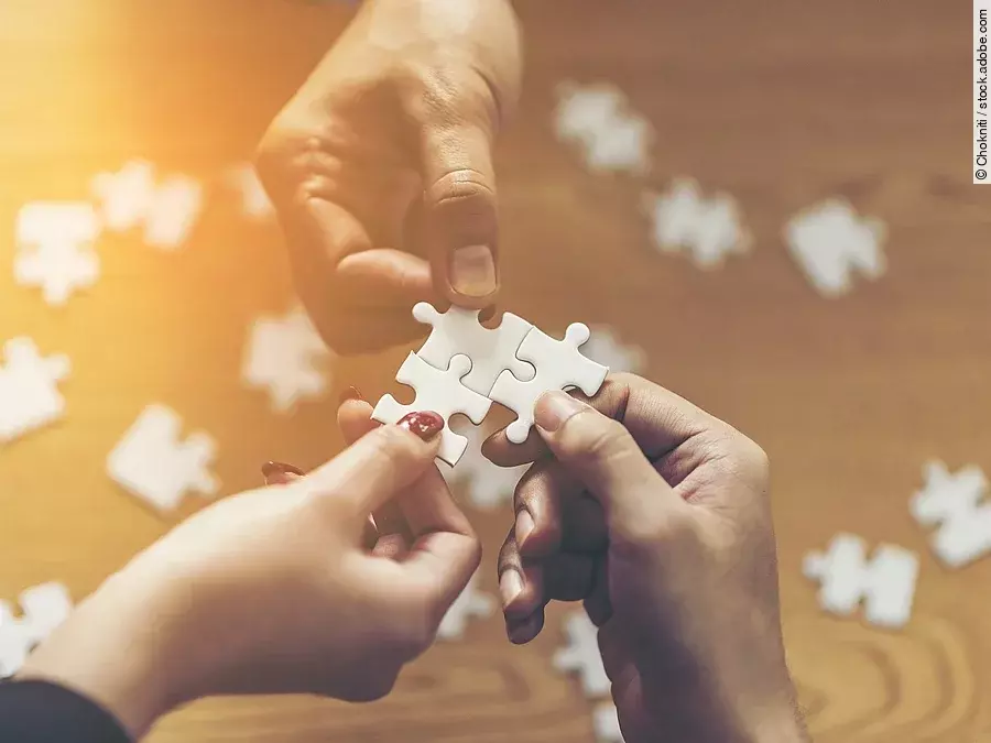Drei Hände setzen drei Puzzlestücke zusammen