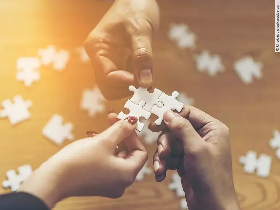 Drei Hände setzen drei Puzzlestücke zusammen
