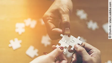 Drei Hände setzen drei Puzzlestücke zusammen