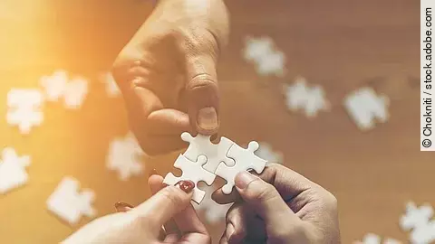 Drei Hände setzen drei Puzzlestücke zusammen